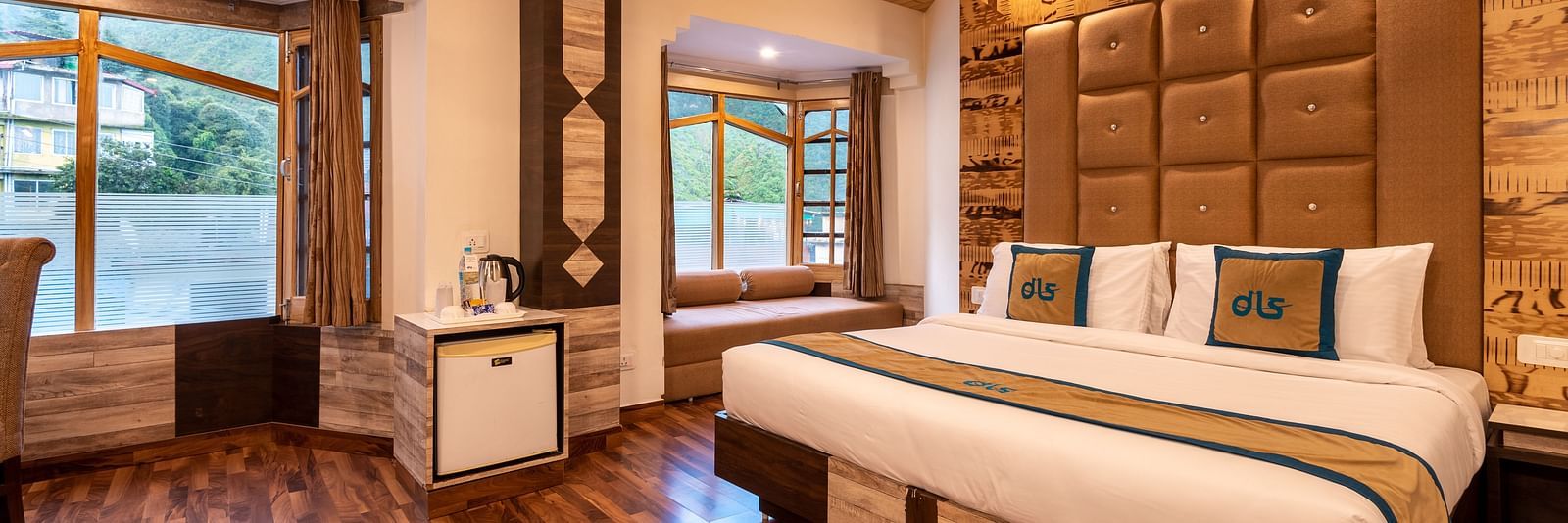 A hotel room in Bhagsunag featuring a large bed, wooden floors, a wooden ceiling, and windows with a view - DLS Meghavan Resort